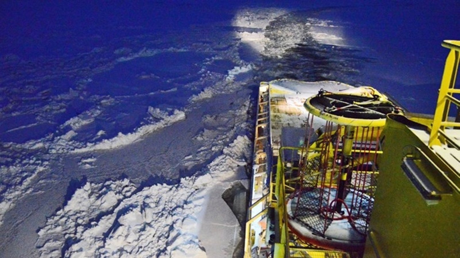 Ship navigating through ice-covered waters at night.